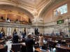 Senate members stand as a ceremonial presentation of colors is done virtually on a video screen above Monday, Jan. 11, 2021, at the Capitol in Olympia, Wash. 