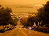 Under darkened skies from wildfire smoke, a man crosses Hyde Street with Alcatraz Island and Fisherman's Wharf in the background Wednesday in San Francisco.