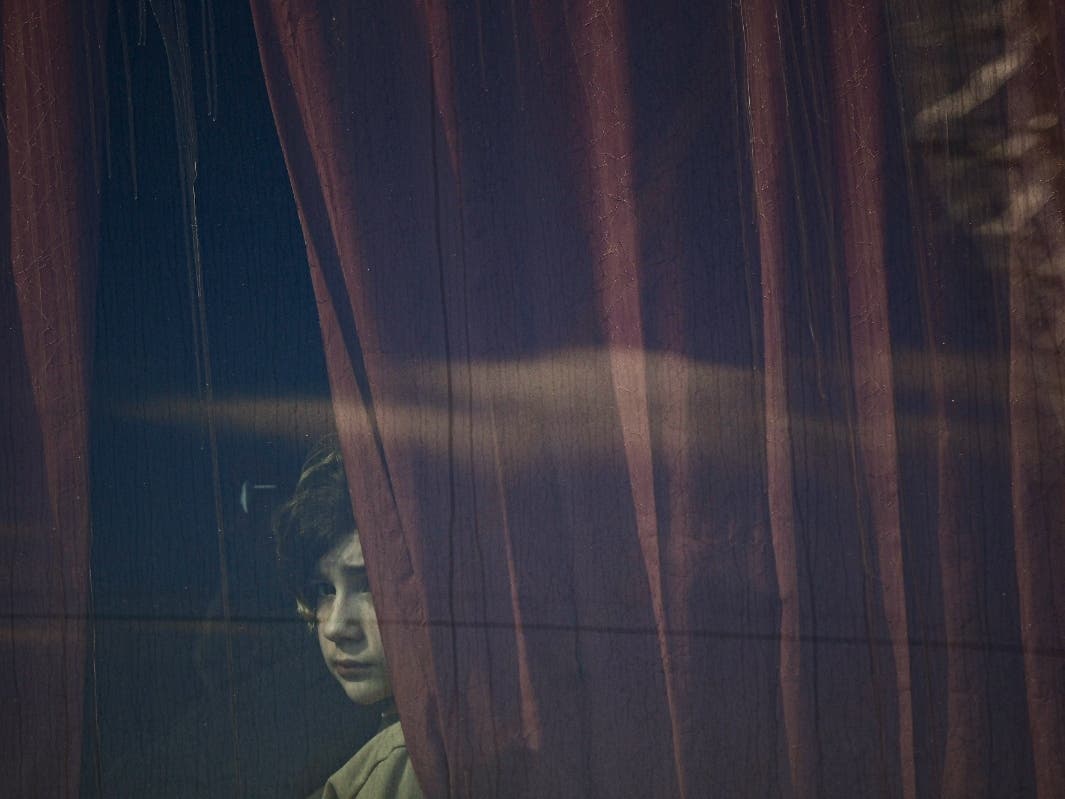 A refugee fleeing the war from neighboring Ukraine looks out a bus window after crossing the border, at the Romanian-Ukrainian border, in Siret, Romania, Monday, March 14, 2022. 