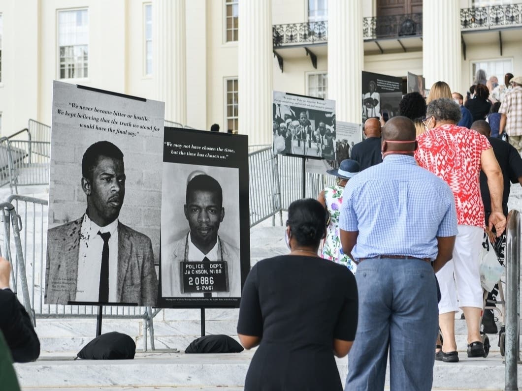 People walk past historic photos as they wait in line to view the body of Congressman John Lewis in the Alabama Capitol Sunday, July 26, 2020, in Montgomery, Alabama.