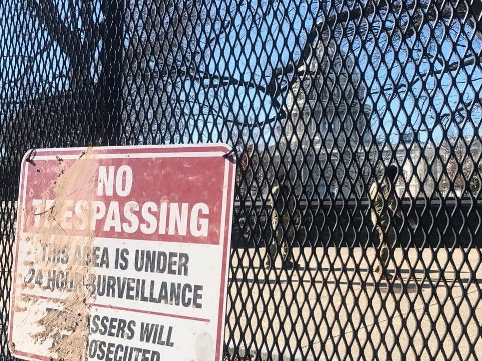 Members of the National Guard stand inside anti-scaling fencing that surrounds the Capitol complex, Sunday, Jan. 10, in Washington.