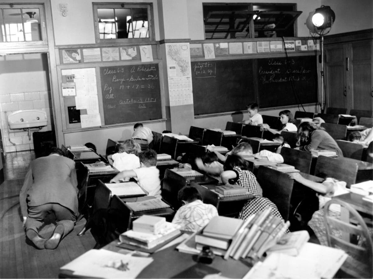 In this Nov. 21, 1951 file picture, sixth graders in Queens, New York crouch under or beside their desks along with their teacher, Vincent M. Bohan, left, as they act out a scene from the Federal Civil Defense administration film "Duck and Cover." 