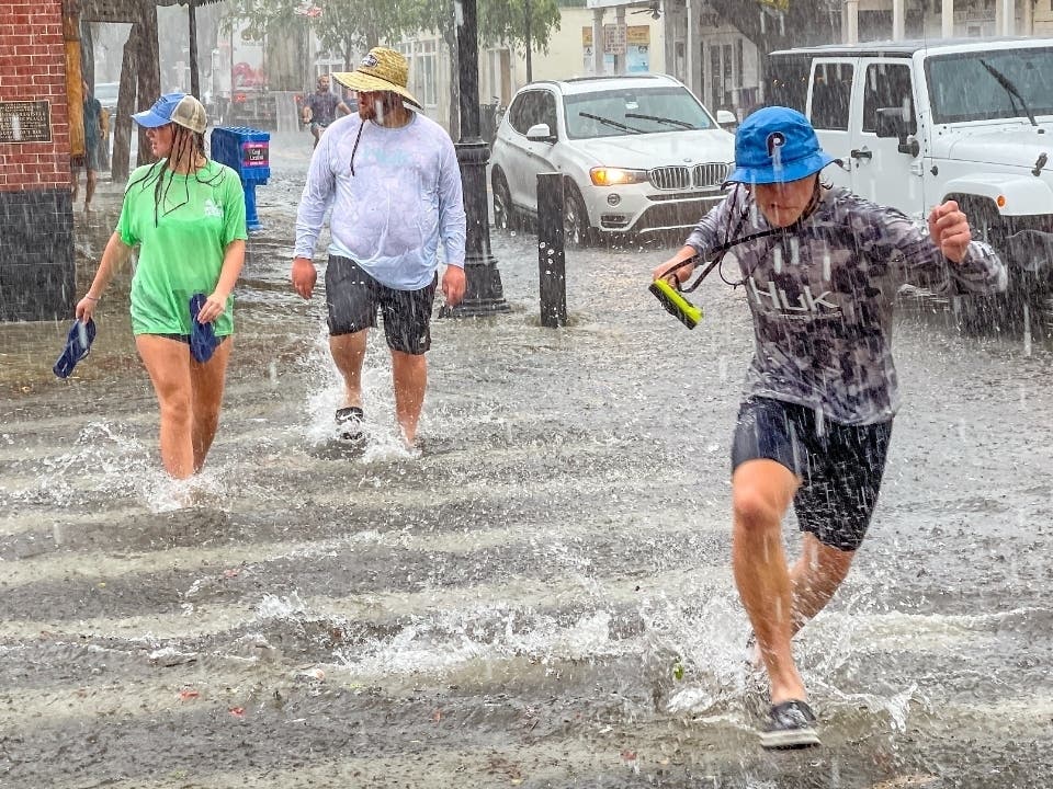 Pedestrians dash across the intersection of Greene and Duval streets as heavy winds and rain associated with Tropical Storm Elsa passes Key West, Florida, on Tuesday.