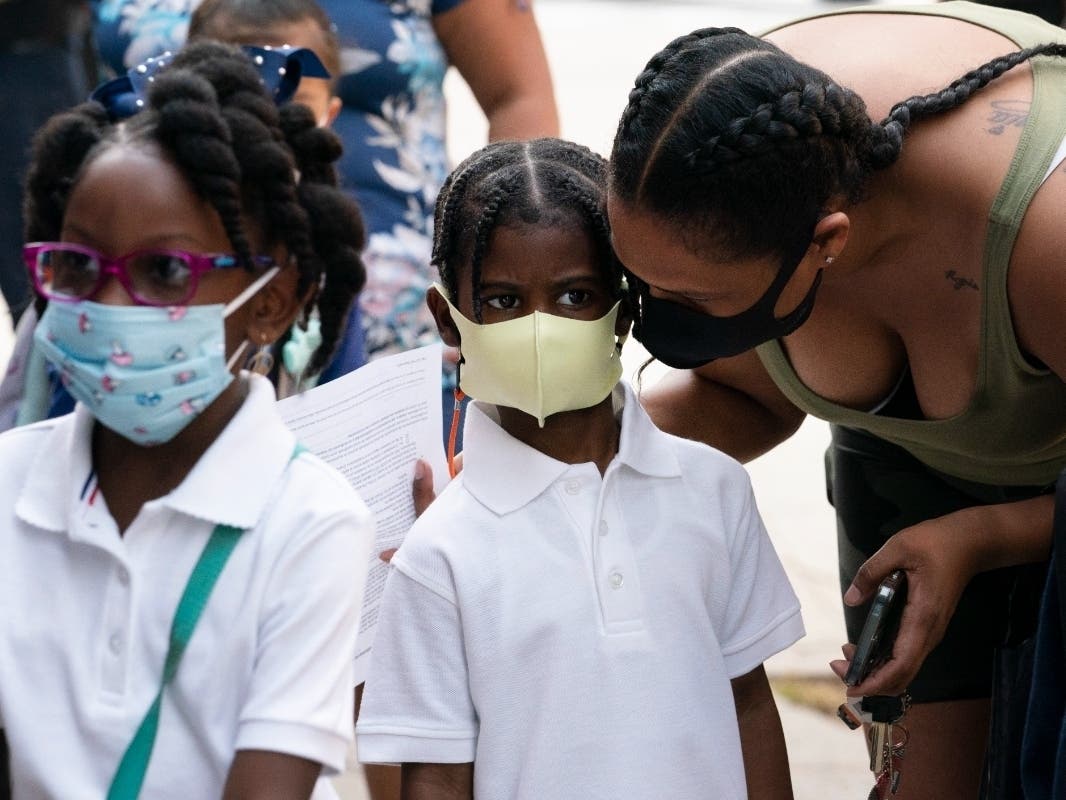 A mother talks with her son as he arrives for the first day of school at Brooklyn's PS 245 on Monday. Classroom doors are swinging open for about a million New York City public school students in the nation's largest experiment of in-person learning.
