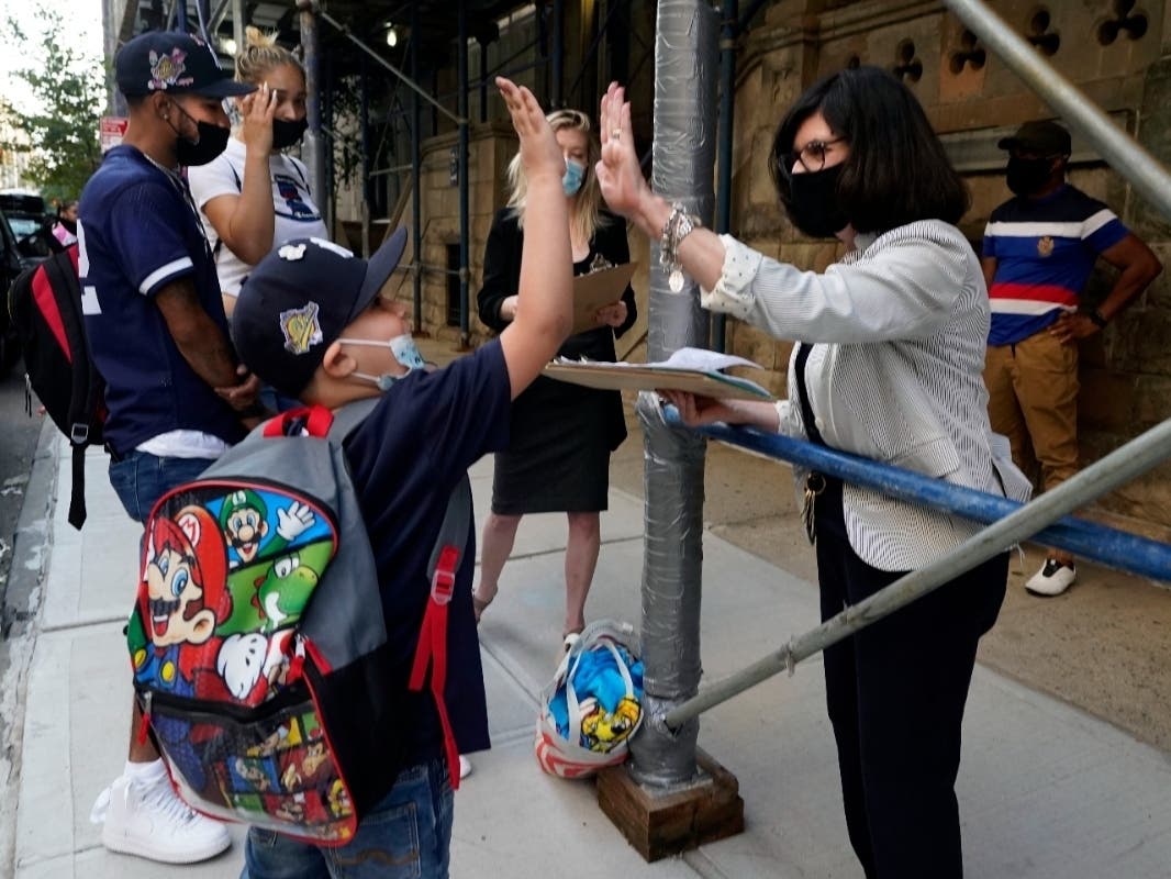 Wilfredo Padilla Jr., 7, a second-grader at PS811 in New York, gets a high-five from Alternative Assessment Coordinator Patricia Valentino, as he arrives for the first day of school on Sept. 13.