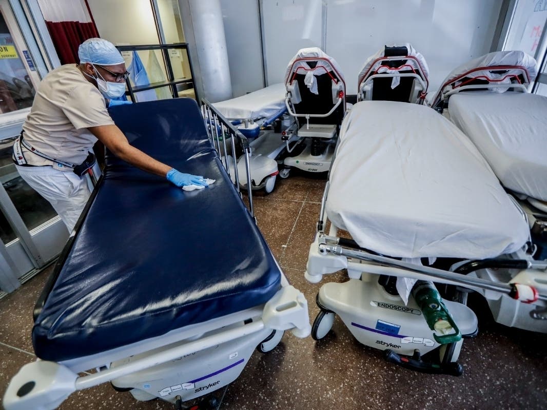 A medical worker wearing personal protective equipment cleans gurneys in the emergency department intake area at NYC Health + Hospitals Metropolitan on May 27, 2020.