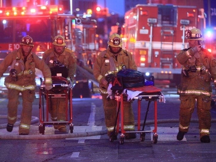 Los Angeles Fire Department firefighters push ambulance cots at the scene of a structure fire that injured multiple firefighters, according to a fire department spokesman, Saturday in Los Angeles.