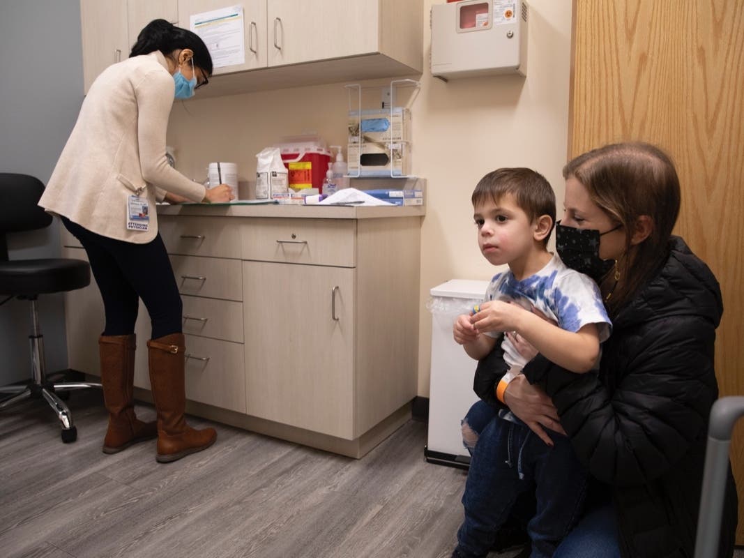 Ilana Diener holds her 3-year-old son during an appointment for a Moderna COVID-19 vaccine trial in November. 
