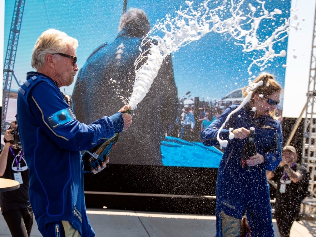 Virgin Galactic founder Richard Branson, left, sprays champagne to crew member Beth Moses, a native of Northbrook, Sunday while celebrating their flight to space from Spaceport America near Truth or Consequences, New Mexico.