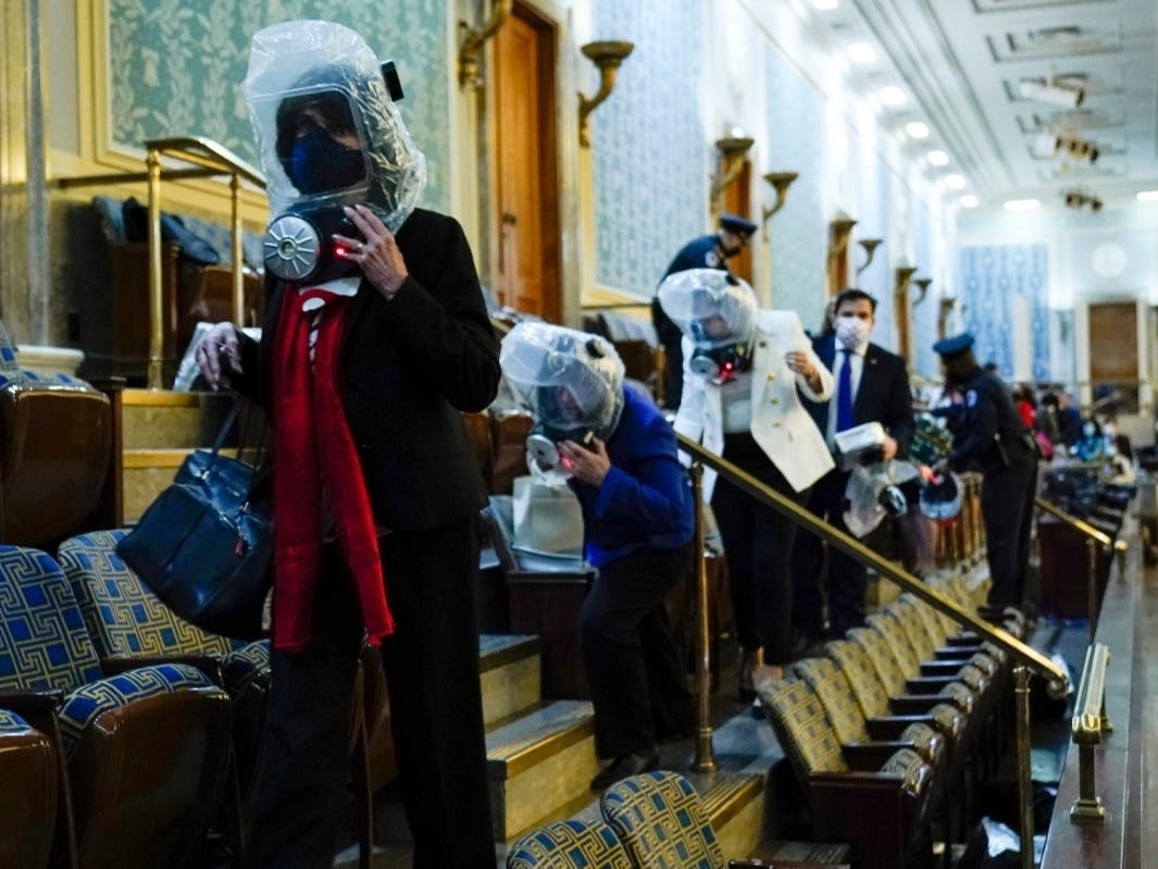 People shelter in the House gallery as protesters try to break into the House Chamber at the U.S. Capitol on Wednesday, Jan. 6, 2021, in Washington.