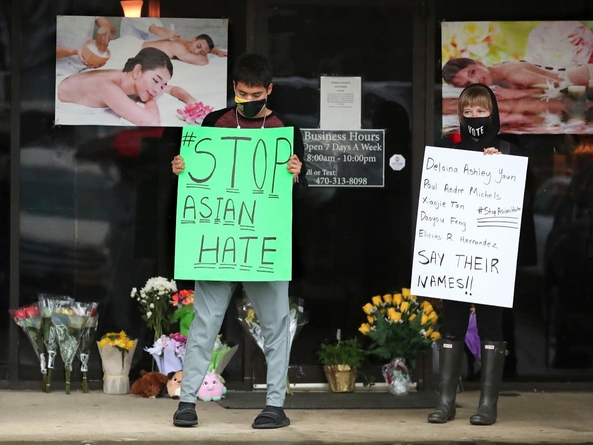 In this March 17, 2021, file photo, after dropping off flowers Jesus Estrella, left, and Shelby stand in support of the Asian and Hispanic community outside Young's Asian Massage in Acworth, Ga. 