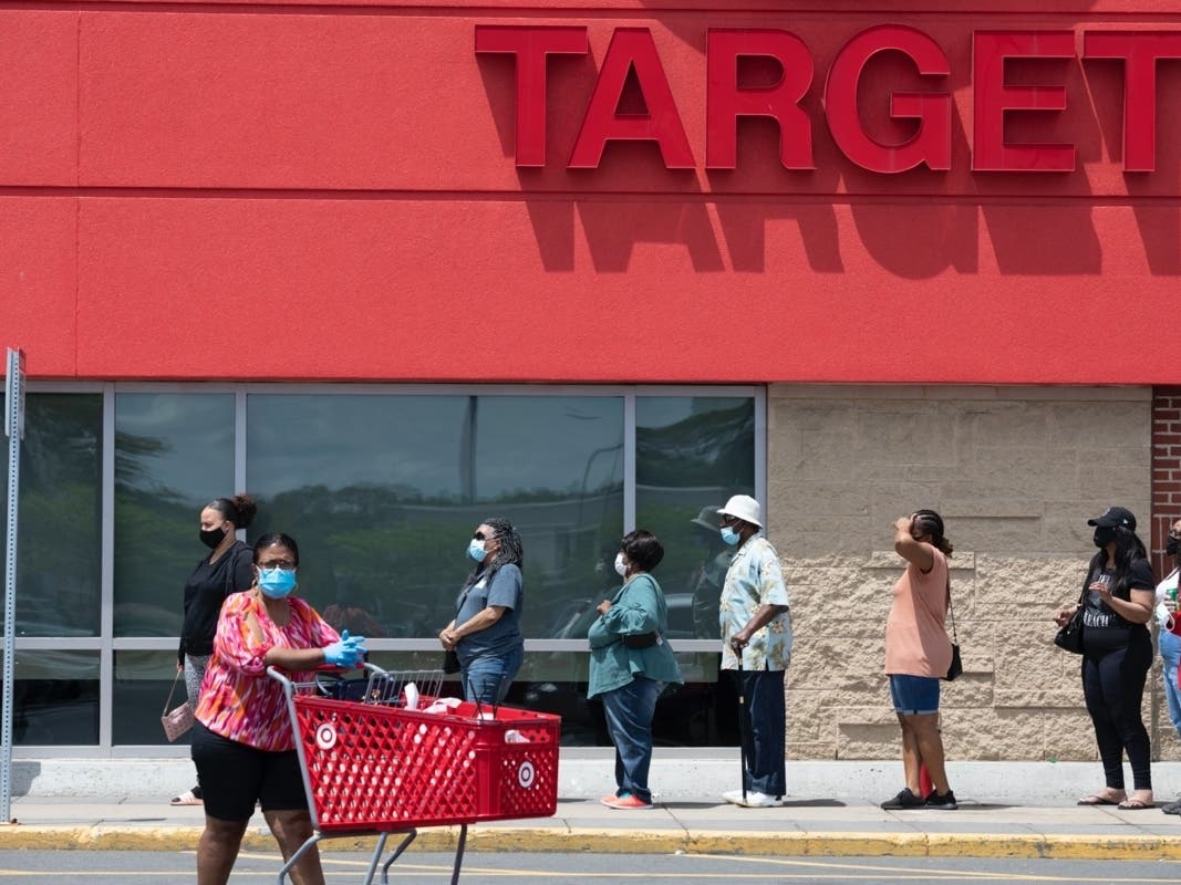People in protective masks line up to enter a Target store Saturday in Boston. 