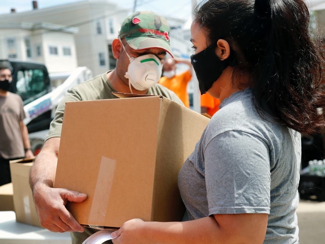 A woman receives a box of food Tuesday, June 2, 2020 at a pop-up pantry in Chelsea, Mass. 