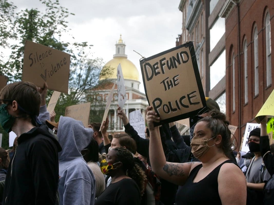 People hold signs during a protest against police brutality Sunday in Boston, triggered by the death of George Floyd, who died May 25 after being restrained by police in Minneapolis.