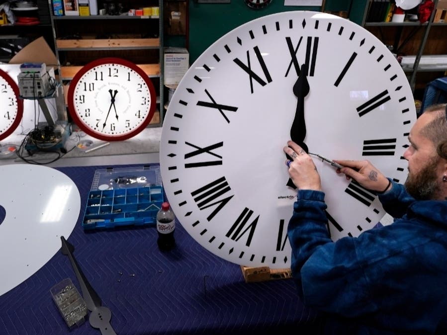 Ian Roders fastens the hands to a clock at Electric Time Company, Tuesday, Nov. 1, 2022, in Medfield, Mass. 
