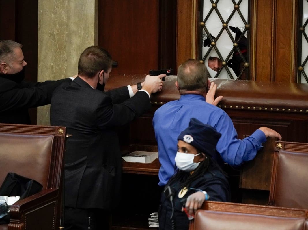 Police with guns drawn watch as protesters try to break into the House Chamber at the U.S. Capitol on Wednesday, Jan. 6, 2021, in Washington. (AP Photo/J. Scott Applewhite)