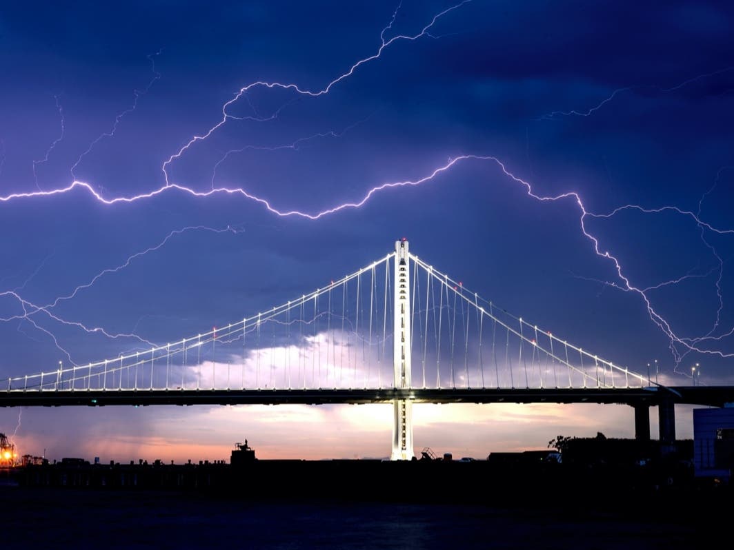 Lightning forks over the San Francisco-Oakland Bay Bridge as a storm passes over Oakland, Calif., Sunday, Aug. 16, 2020. Numerous lightning strikes early Sunday sparked brush fires throughout the region.