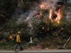 Ben Slaughter, a firefighter for the Boulder Creek Fire Department, walks along Highway 9 while monitoring flames from the CZU August Lightning Complex Fire, Saturday, Aug. 22, 2020, in Boulder Creek, Calif.