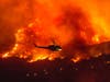 A helicopter prepares to drop water at a wildfire in Yucaipa, Calif., Saturday. Three fast-spreading California wildfires sent people fleeing Saturday, with one trapping campers at a reservoir in the Sierra National Forest.