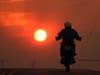 A man rides a motorcycle down Cima Mesa Rd. as the sun sets while crews battle the Bobcat Fire Friday, Sept. 18, 2020, in Juniper Hills, Calif. 