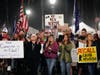 Demonstrators listen to a speaker Saturday, Nov. 21, 2020 during a protest against a stay-at-home order amid the COVID-19 pandemic in Huntington Beach, Calif.