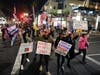 Demonstrators march across Pacific Coast Highway while shouting slogans Saturday, Nov. 21, 2020 during a protest against a stay-at-home order amid the COVID-19 pandemic in Huntington Beach, Calif.
