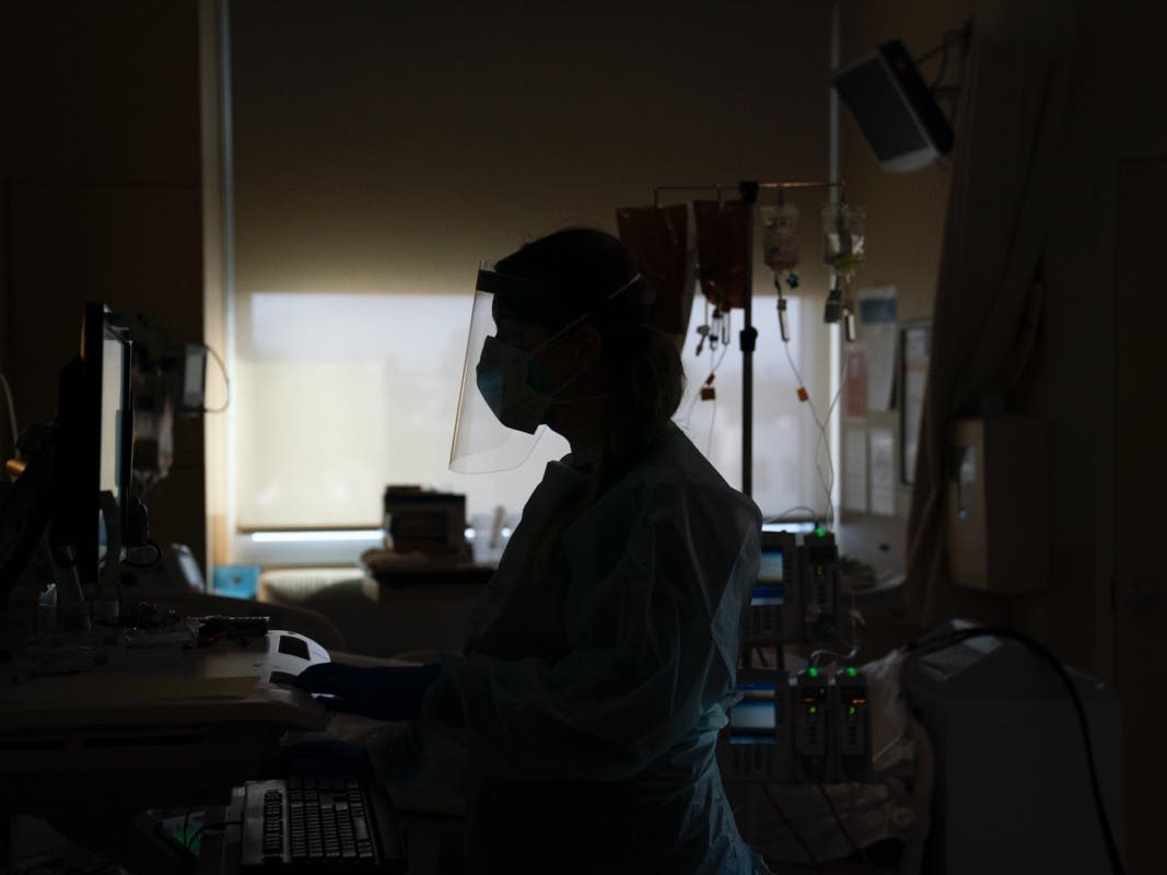  In this Nov. 19, 2020, file photo, registered nurse Virginia Petersen works on a computer while assisting a COVID-19 patient at Providence Holy Cross Medical Center in the Mission Hills section of Los Angeles. 
