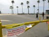 Pedestrians walk through an empty parking lot at Venice Beach, Saturday, March 28, 2020, in Los Angeles.