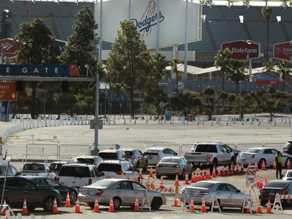 Cars wait in line as they enter a COVID-19 vaccination site at Dodger Stadium in Los Angeles, on Thursday, Feb. 25, 2021. 
