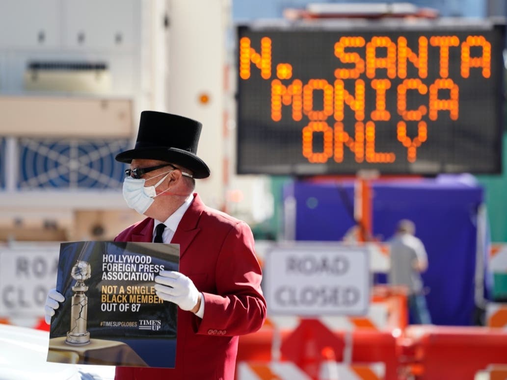 Gregg Donovan demonstrates with a sign protesting the lack of Black members in the Hollywood Foreign Press Association, outside a road closure near the 78th Golden Globe Awards at the Beverly Hilton, Sunday, Feb. 28, 2021, in Beverly Hills, Calif. 