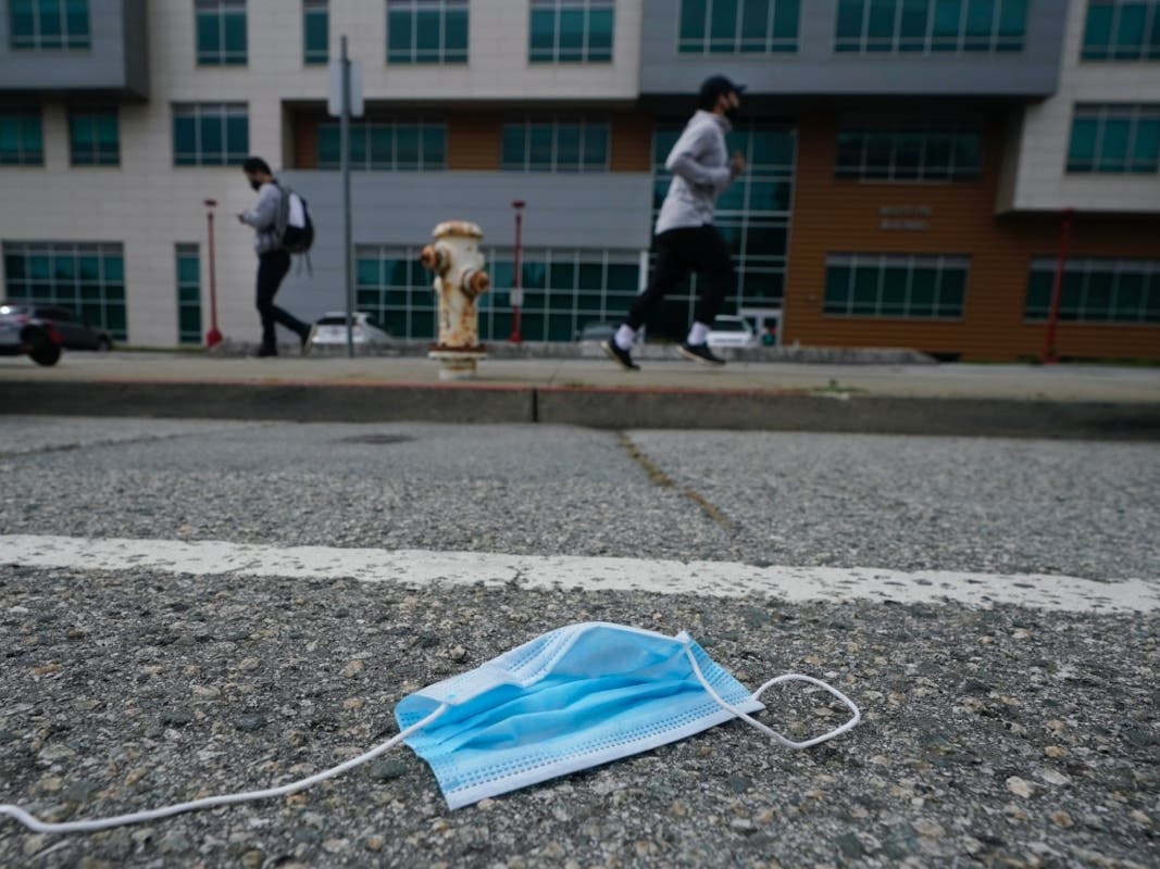 A discarded face mask lies in the street in San Francisco, Wednesday, March 17, 2021. Disposable masks, gloves and other personal protective equipment have safeguarded untold lives during the pandemic. 