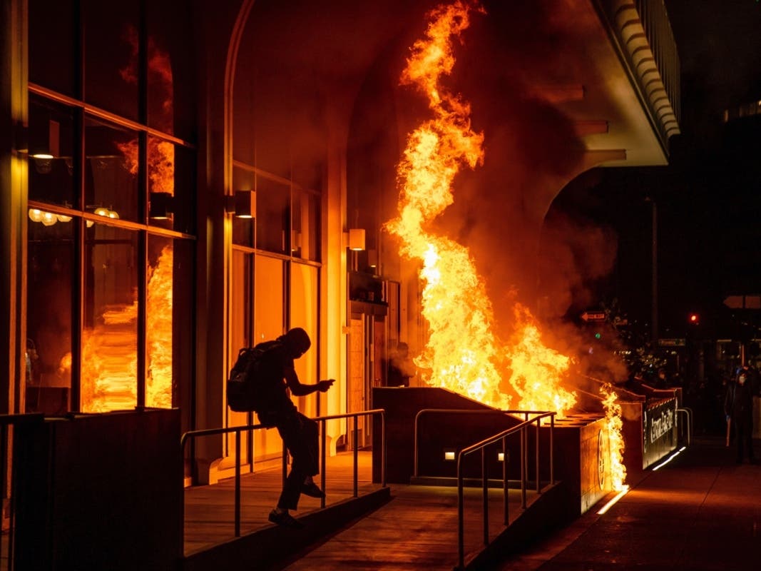 Demonstrators set fire to the front of the California Bank and Trust building during a protest against police brutality in Oakland, Calif., Friday, April 16, 2021.