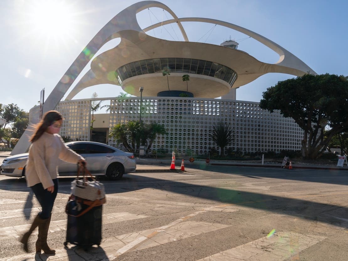 A traveler walks past The Theme Building at Los Angeles International Airport in Los Angeles, Wednesday, Nov. 25, 2020. 