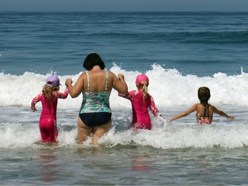 A woman and children wade into the surf in Hermosa Beach, Calif., as a record-setting heat wave hit Southern California Friday, July 6, 2018. 