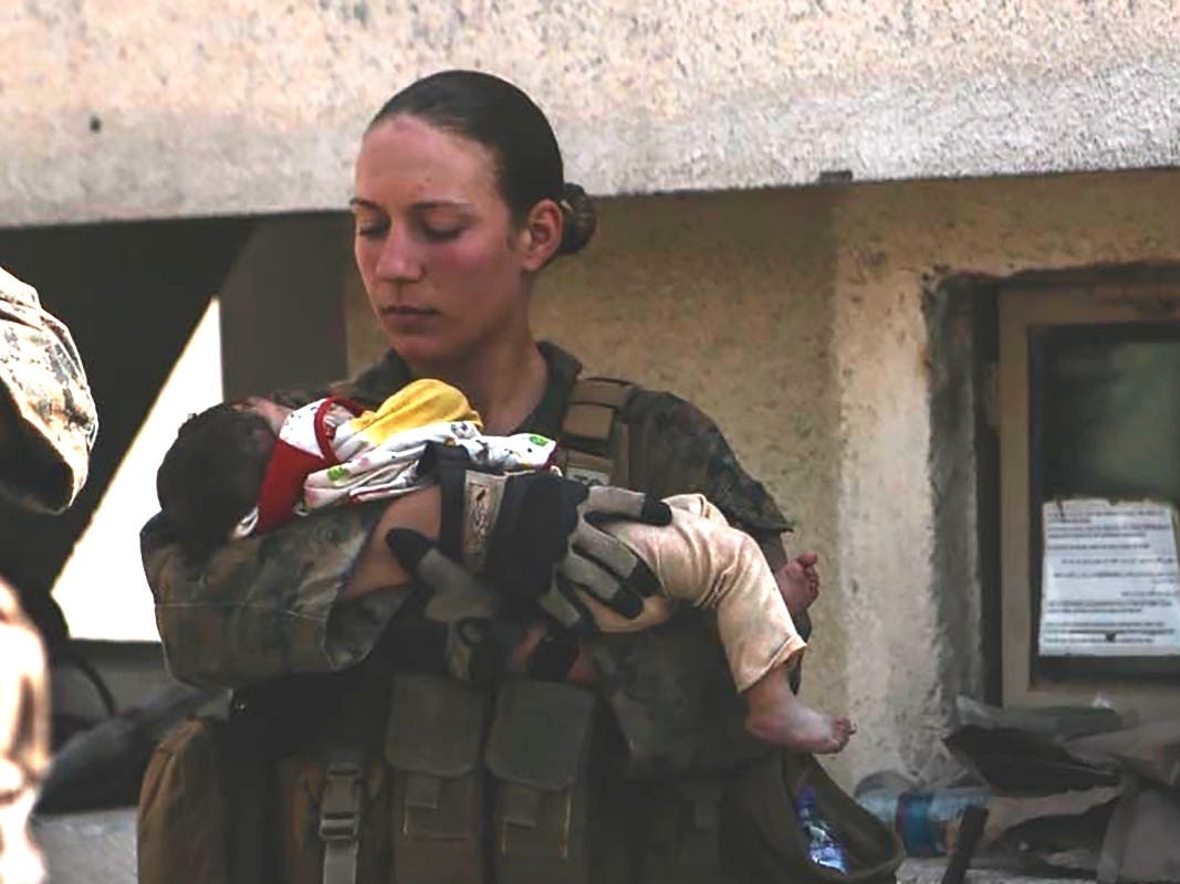 This undated photo provided by U.S. Department of Defense twitter page posted Aug. 20, 2021 shows Sgt. Nicole Gee holding a baby at Hamid Karzai International Airport in Kabul, Afghanistan.