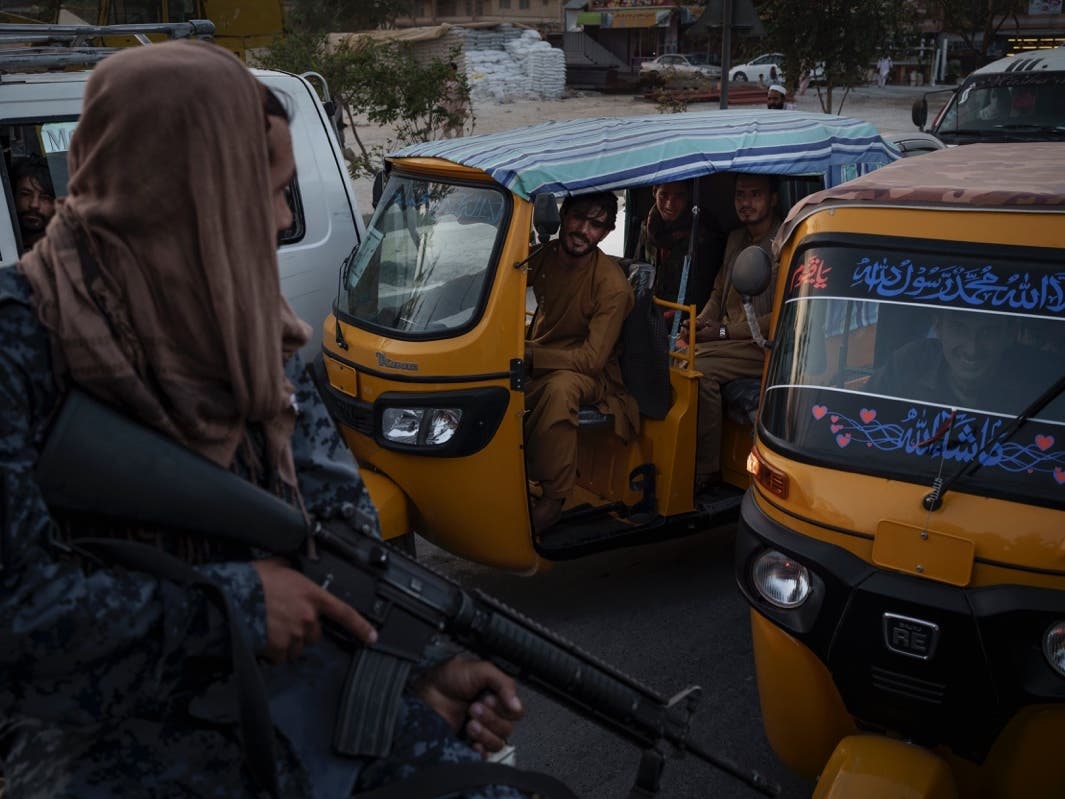 Afghan drivers and passengers stuck in a traffic jam look at Taliban fighters riding in the back of a pickup truck in Kabul, Afghanistan, Monday, Sept. 20, 2021. 