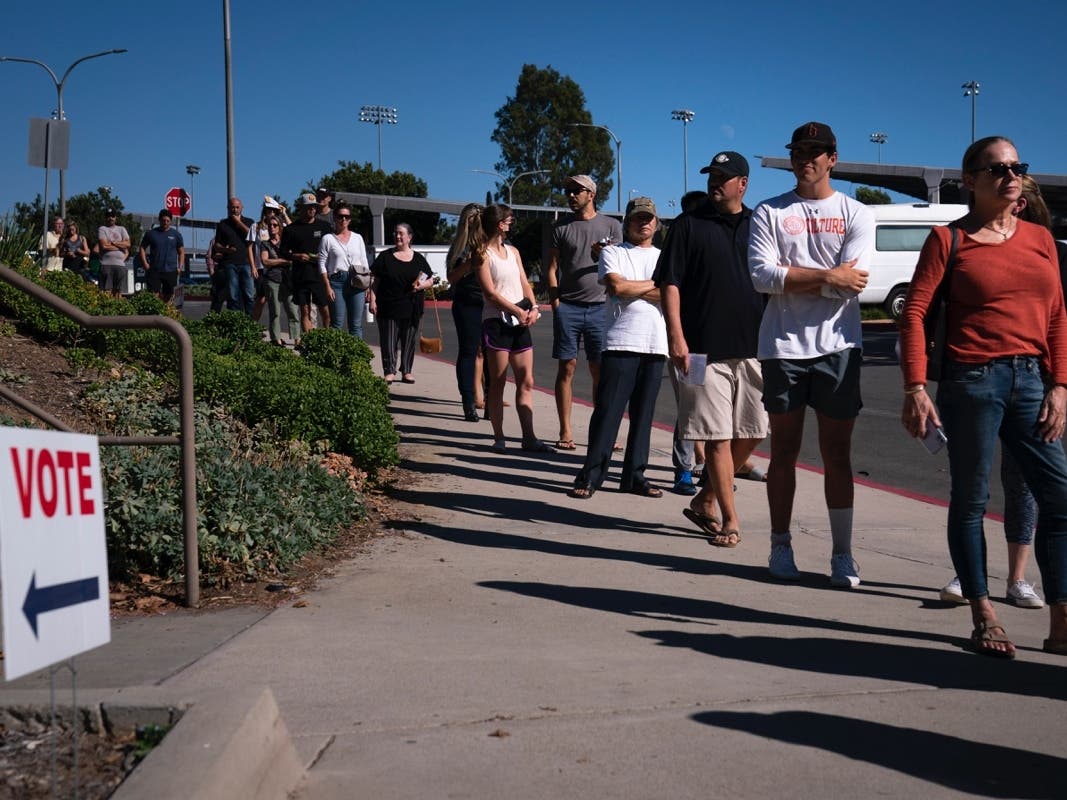 In this Sept. 14, 2021, file photo, people wait in line outside a voting center to cast their recall ballots in Huntington Beach, Calif. 