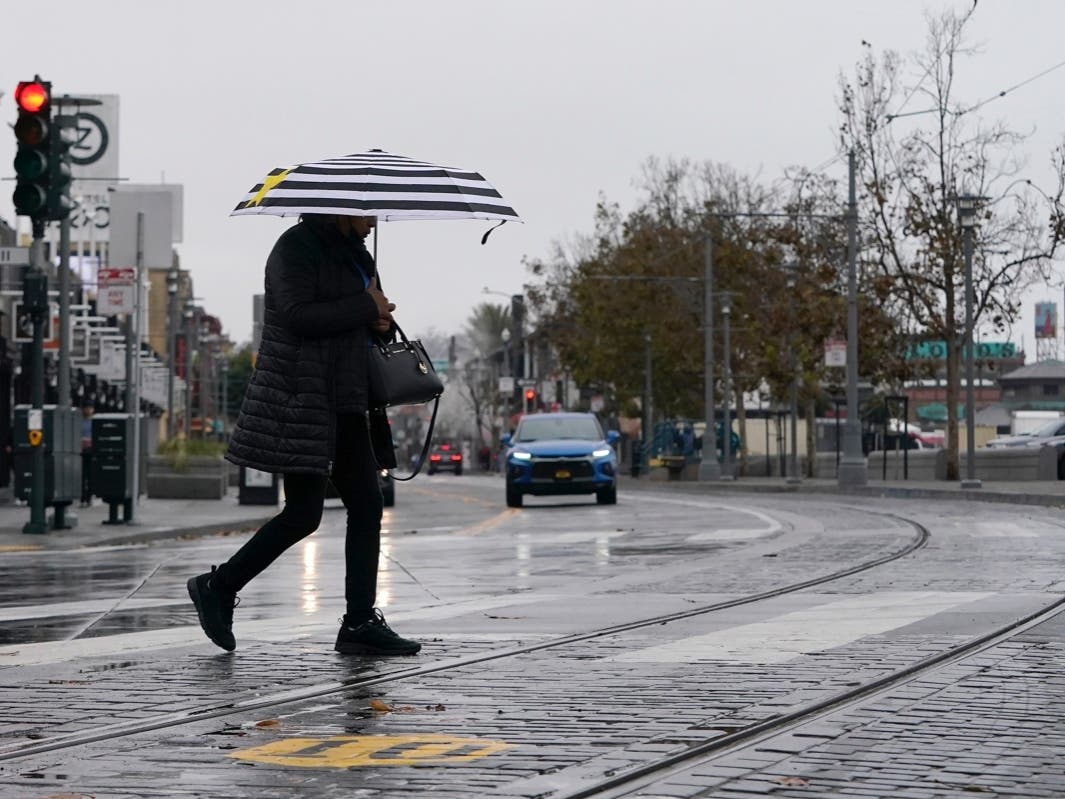 A pedestrian carries an umbrella while crossing a street at Fisherman's Wharf in San Francisco.