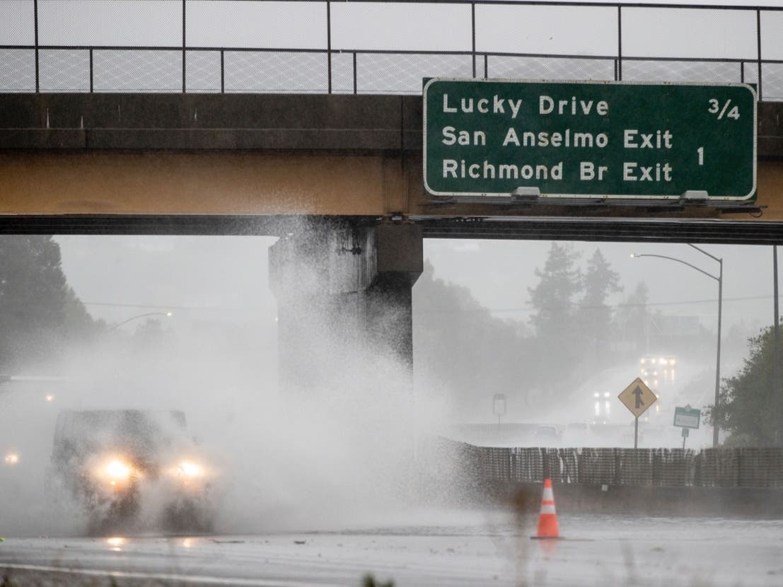 A car drives on Highway 101, which is partially flooded in Corte Madera, Calif., Sunday, Oct. 24, 2021.