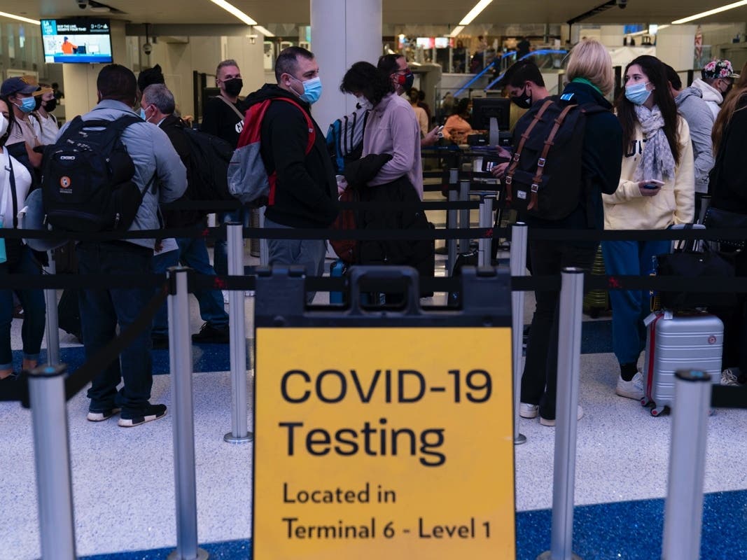 Travelers wait in line for screening at a COVID-19 testing site at the Los Angeles International Airport Wednesday.