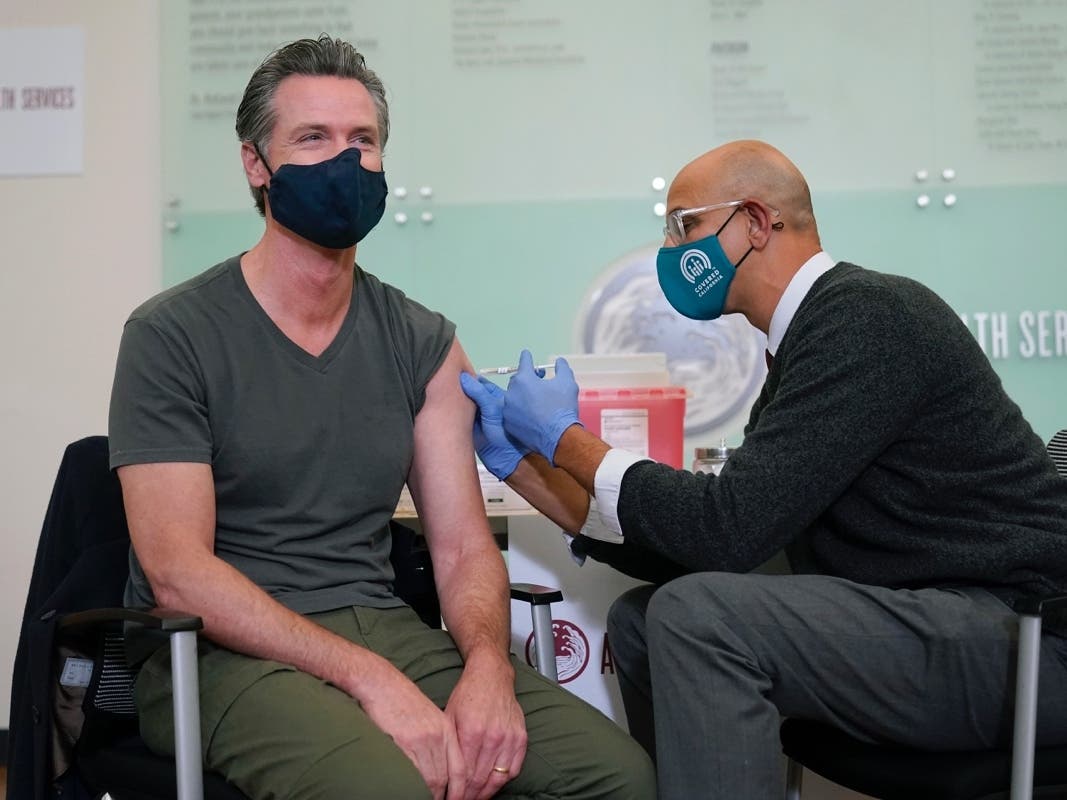 California Gov. Gavin Newsom, left, receives a Moderna COVID-19 vaccine booster shot from California Health and Human Services Secretary Dr. Mark Ghaly at Asian Health Services in Oakland, Calif.