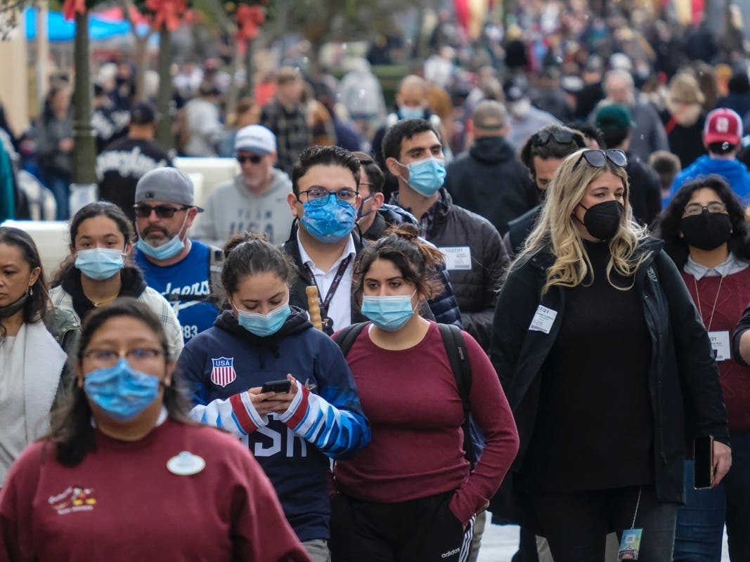 Visitors wearing face masks walk down Main Street USA at Disneyland in Anaheim, Calif., Monday