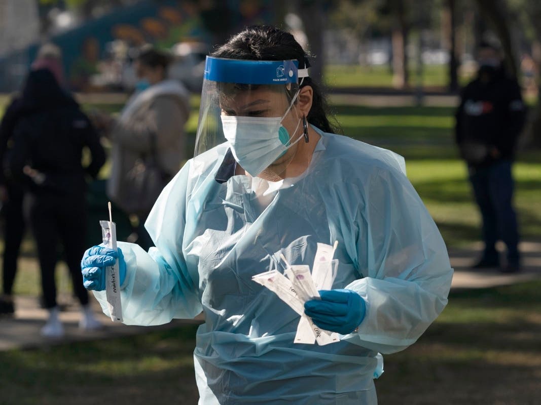 Medical assistant Leslie Powers carries swab samples collected from people to process them on-site at a COVID-19 testing site in Long Beach, Calif., Thursday, Jan. 6, 2022. 
