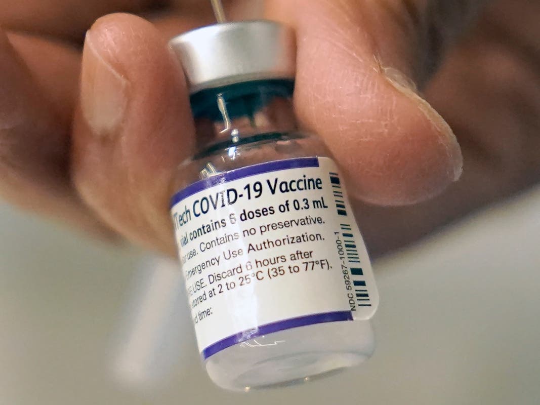 A doctor loads a dose of Pfizer COVID-19 vaccine into a syringe.