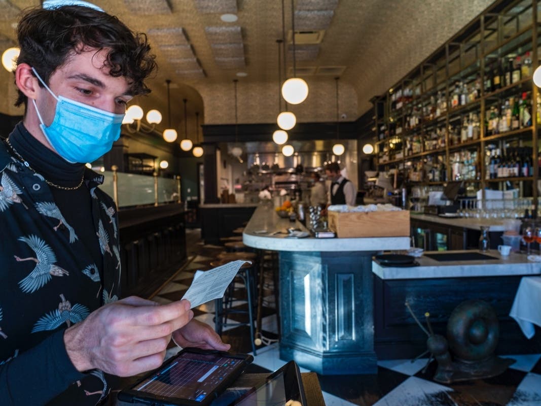 Restaurant host Joey Tyler verifies a patron's vaccination card at French restaurant Petit Trois in Los Angeles.