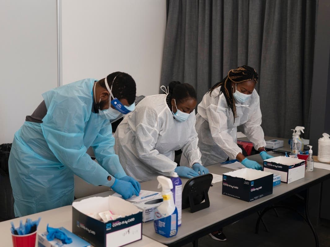 Health care workers Henry Paul (from left), Ray Akindele, Wilta Brutus and Leslie Powers process COVID1-9 rapid antigen tests at a testing site in Long Beach on Thursday.