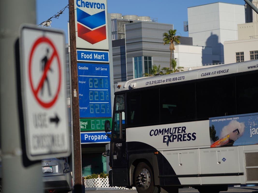 A clean air Commuter Express bus drives past a Chevron gas station in downtown Los Angeles. Gas prices are up nearly 40 percent from a year ago and more than 6 percent over the past month, according to AAA.