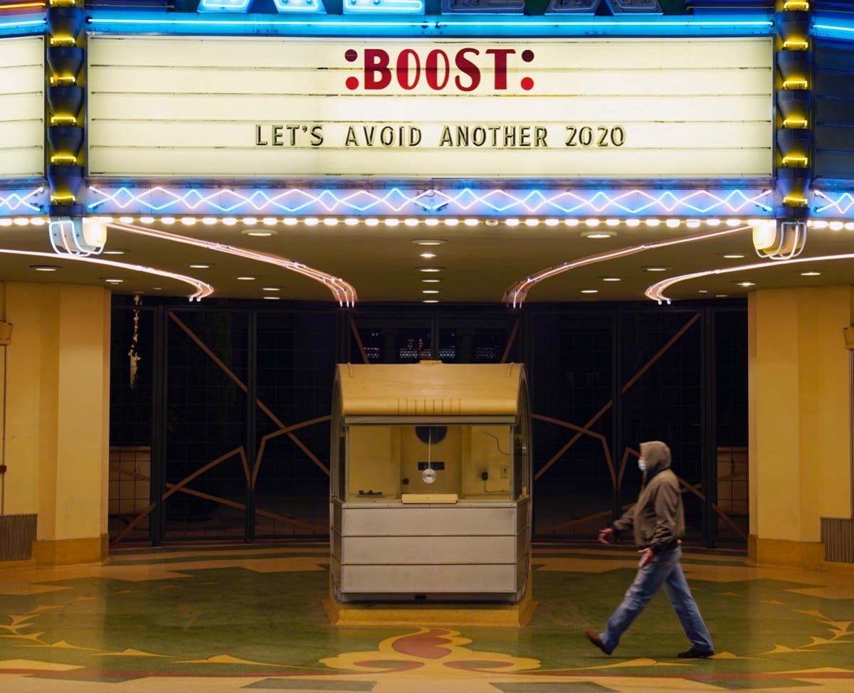 A man walks underneath the marquee of the Alex Theatre in Glendale, Calif.