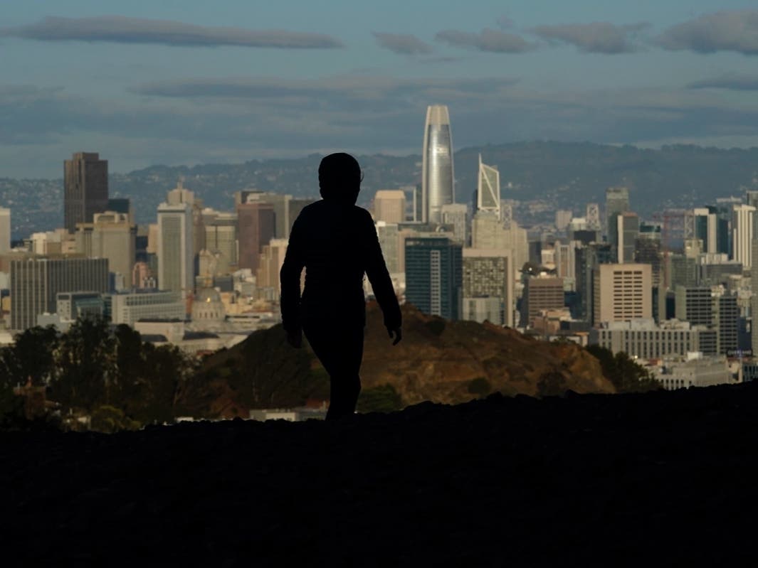 A person walks atop Tank Hill in front of the skyline during the coronavirus pandemic in San Francisco.