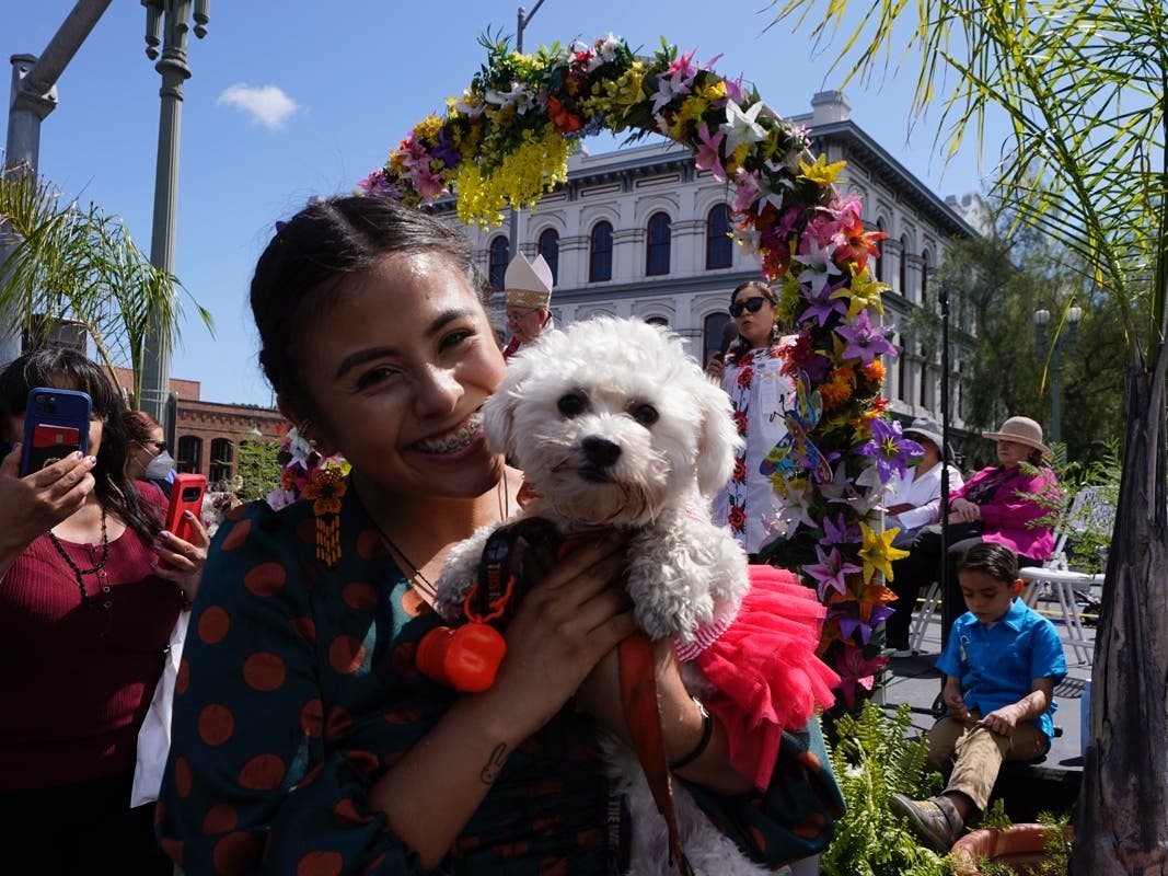 A girl poses with her dog after being blessed by Archbishop Jose H. Gomez during the traditional blessing of animals ceremony at Placita Olvera downtown in Los Angeles Saturday, April 16, 2022. 